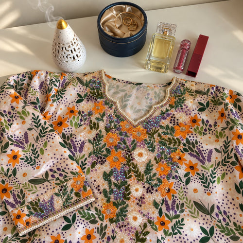 Dahlia laid flat, showing the cream floral print with orange blooms and a beaded V-neckline
