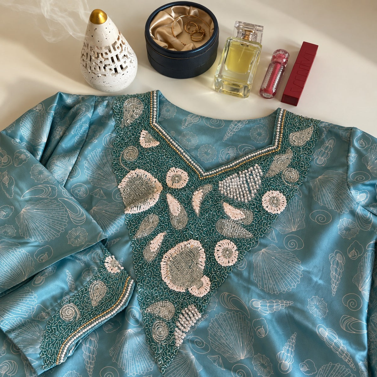 Ocean laid flat, showing the aqua seashell print and teal beaded shell neckline