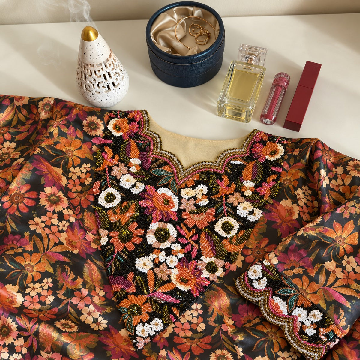 Oud laid flat, showing the charcoal autumn floral print and black beaded panel with daisies