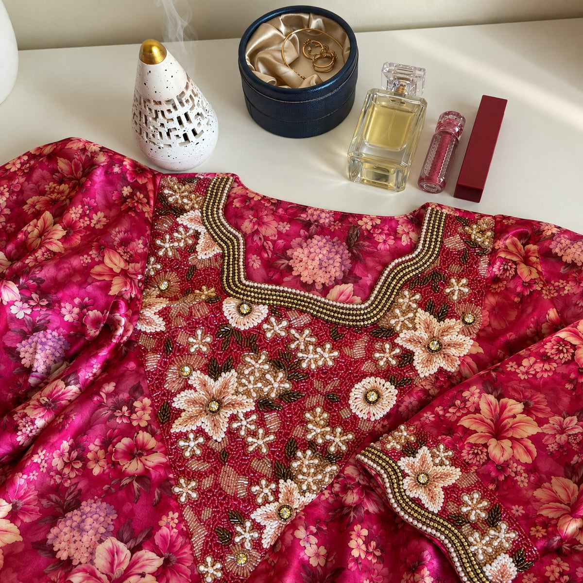 Ruby laid flat, showing the fuchsia floral print and square neckline with layered gold beading